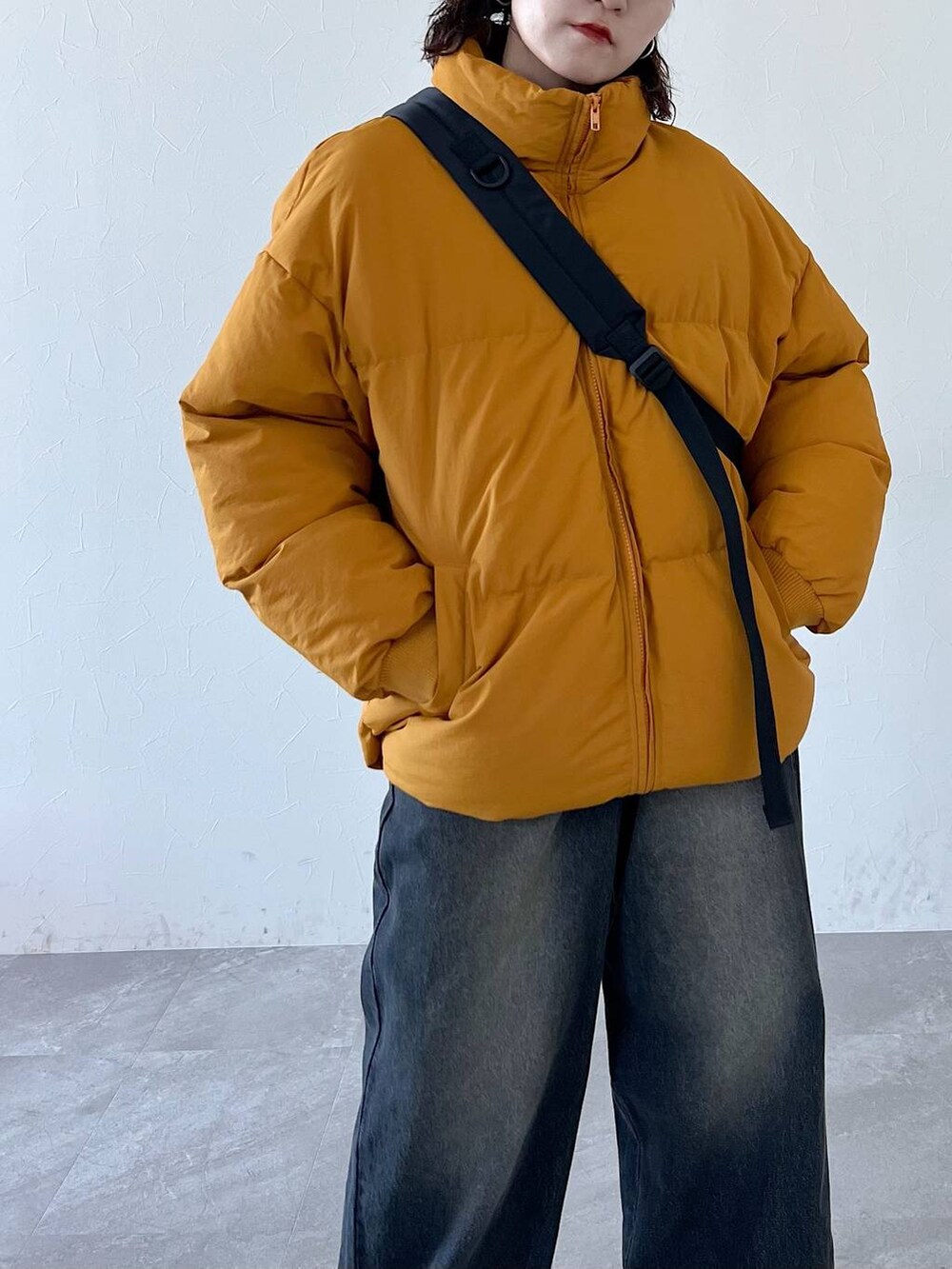 ブラック系のその他シューズ、ブラック系のデニムパンツ、イエロー系のダウンジャケット/コートを着用したレディースの秋コーディネートの3枚目の写真