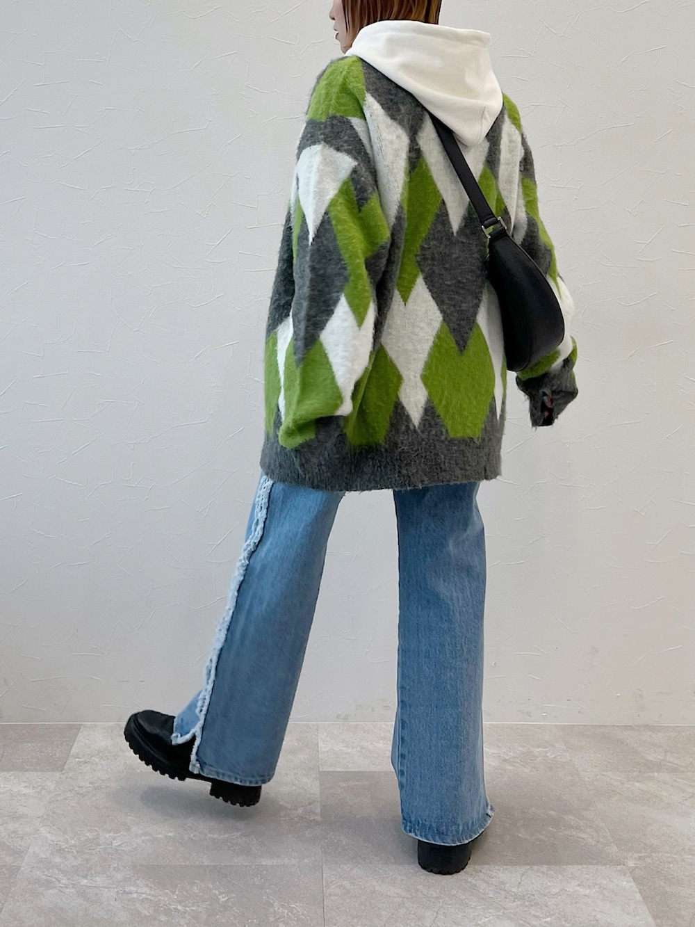 ブルー系のデニムパンツ、ブラック系のブーツ、グリーン系のカーディガン/ボレロを着用したレディースの冬コーディネートの4枚目の写真