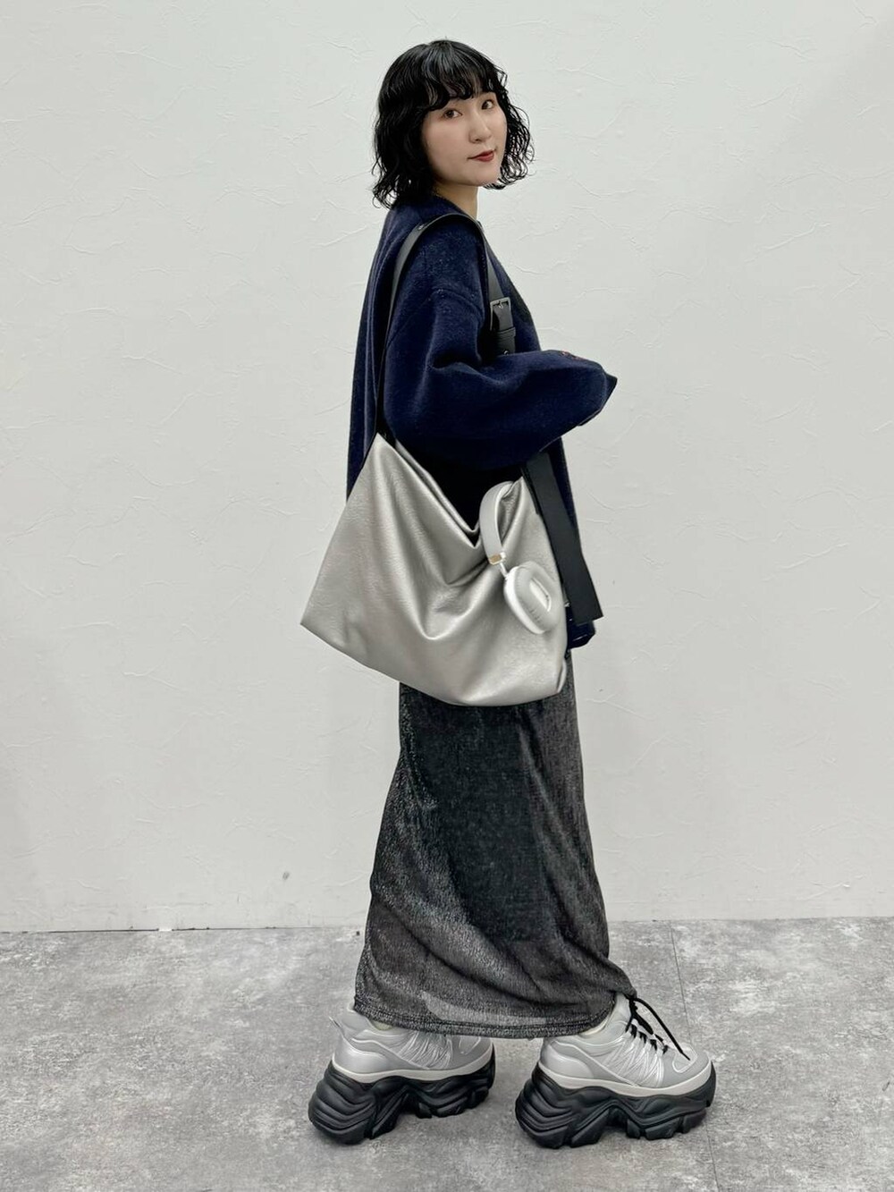 グレー系のスニーカー、シルバー系のトートバッグ、ブラック系のスカートを着用したレディースの秋コーディネートの3枚目の写真