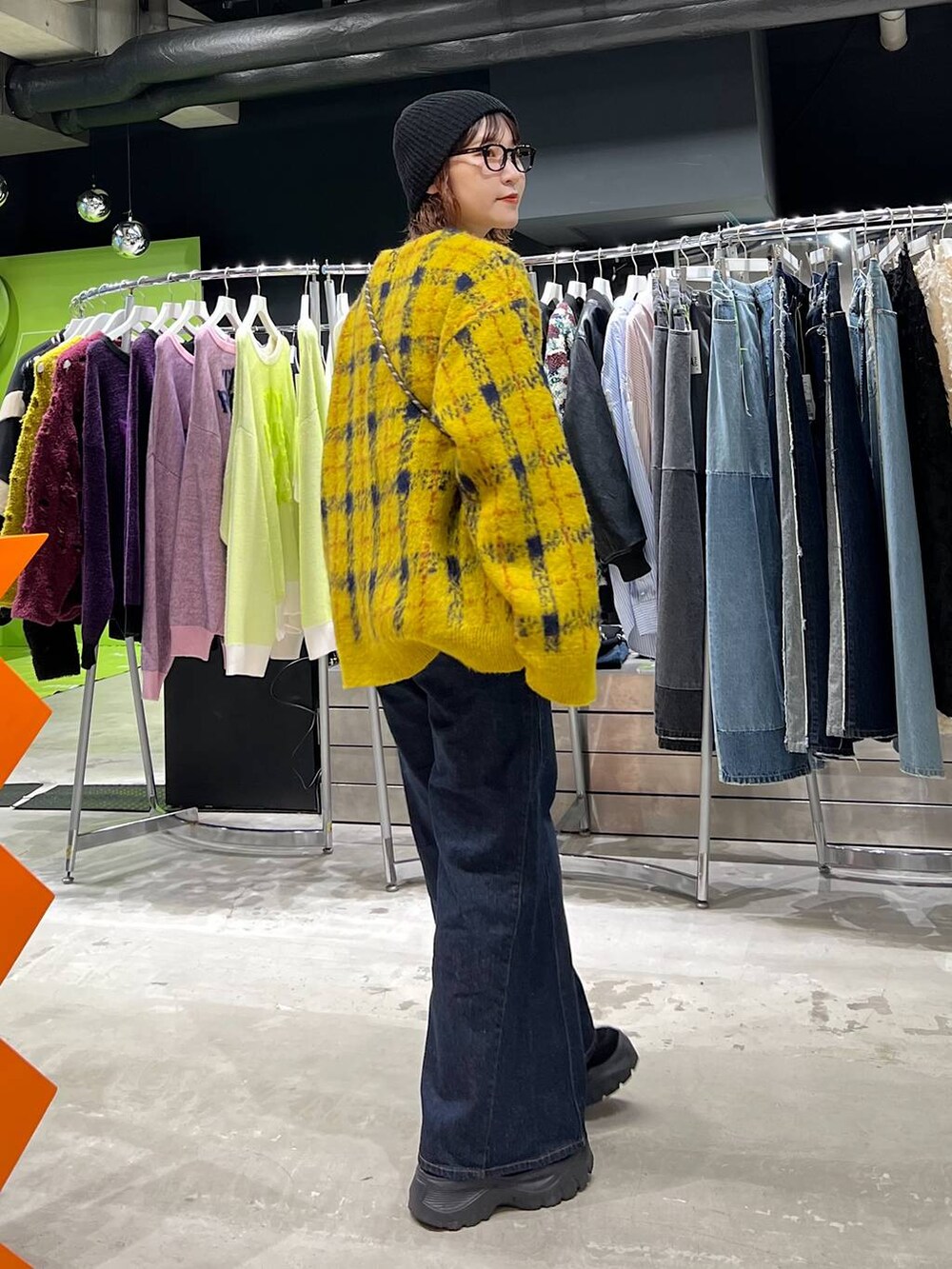 ブルー系のデニムパンツ、イエロー系のカーディガン/ボレロ、ブラック系のニットキャップ/ビーニーを着用したレディースの夏コーディネートの2枚目の写真