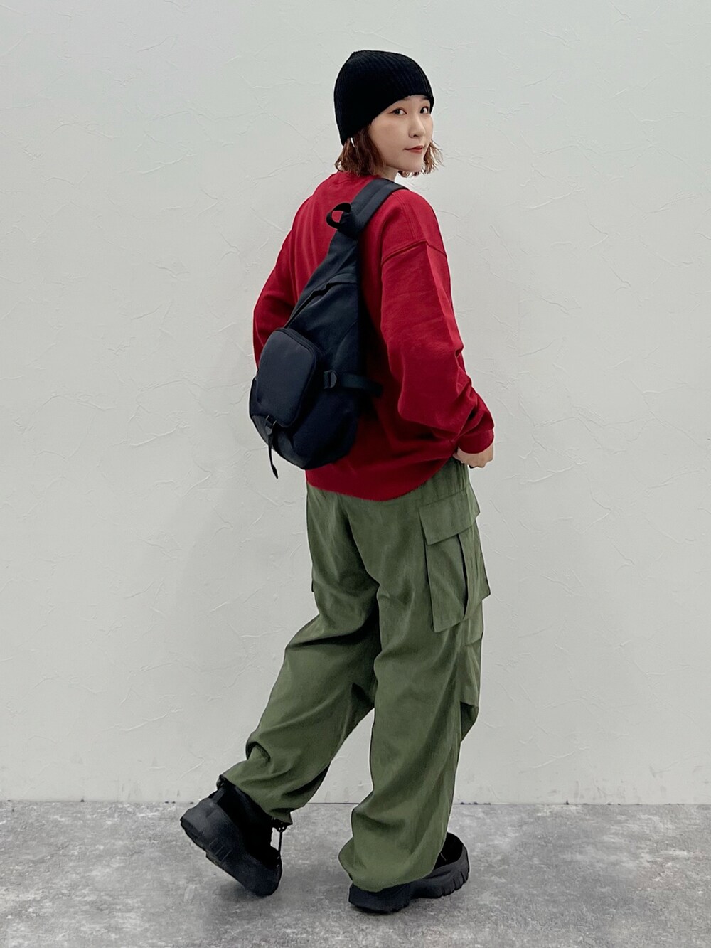 グリーン系のカーゴパンツ、レッド系のスウェット、ブラック系のニットキャップ/ビーニーを着用したレディースの秋コーディネートの2枚目の写真