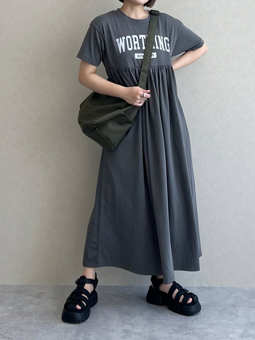 グリーン系のショルダーバッグ、ブラック系のサンダル、グレー系のワンピースを着用したレディースの春コーディネートの3枚目の写真