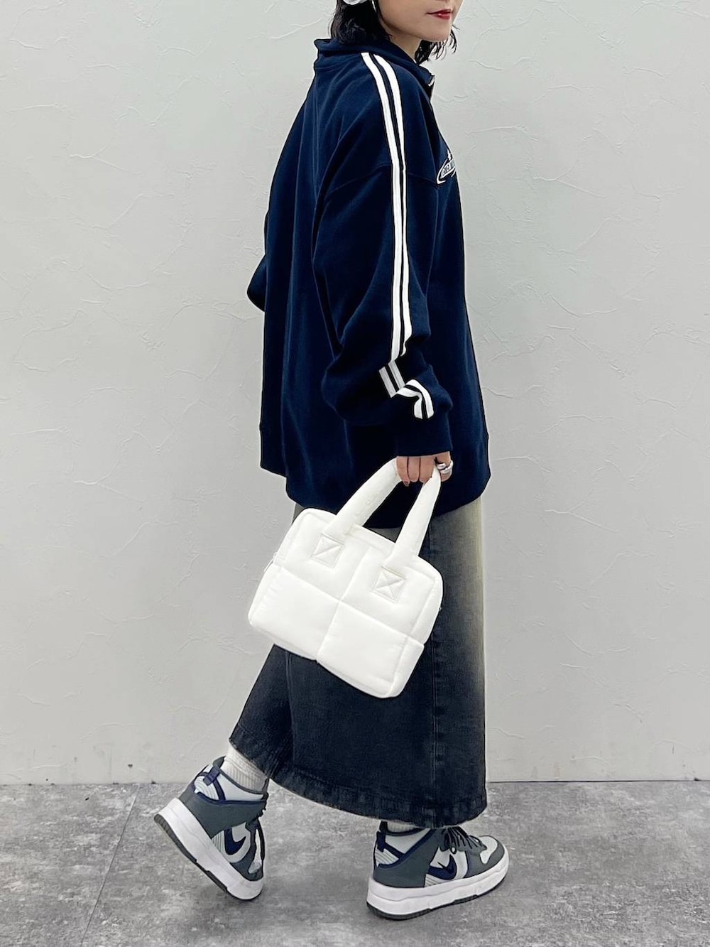 ホワイト系のハンドバッグ、ブラック系のスカート、ブルー系のスウェットを着用したレディースの秋コーディネートの3枚目の写真