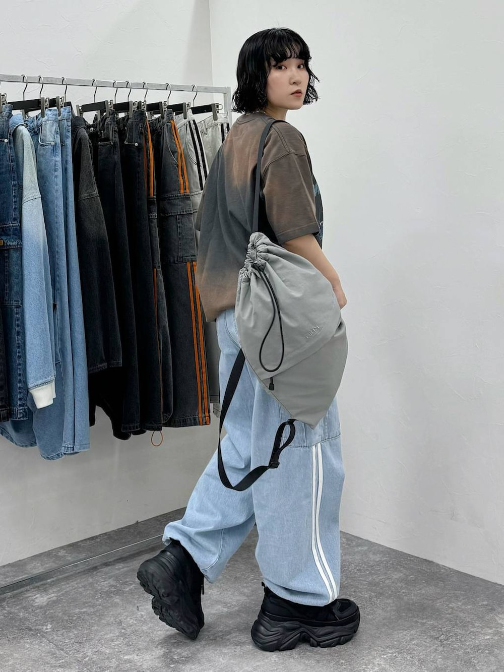 グレー系のバックパック/リュック、ブルー系のデニムパンツ、ブラック系のスニーカーを着用したレディースの春コーディネートの2枚目の写真