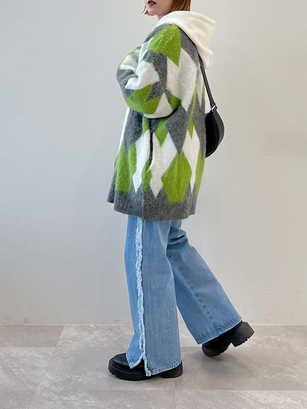 ブルー系のデニムパンツ、ブラック系のブーツ、グリーン系のカーディガン/ボレロを着用したレディースの冬コーディネートの3枚目の写真