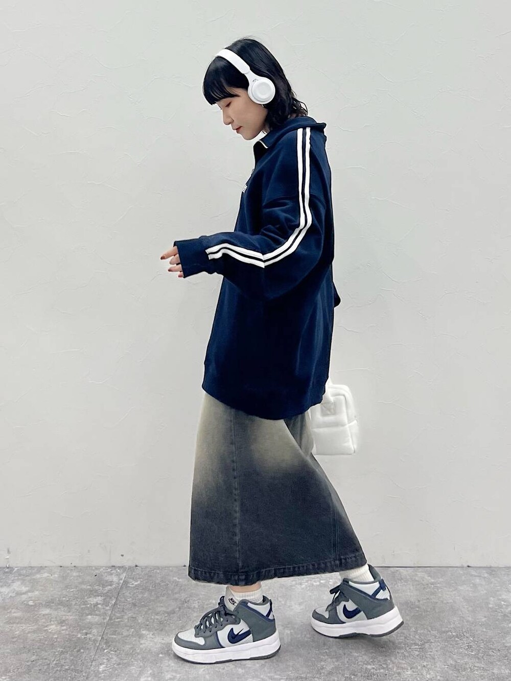 ホワイト系のハンドバッグ、ブラック系のスカート、ブルー系のスウェットを着用したレディースの秋コーディネートの4枚目の写真