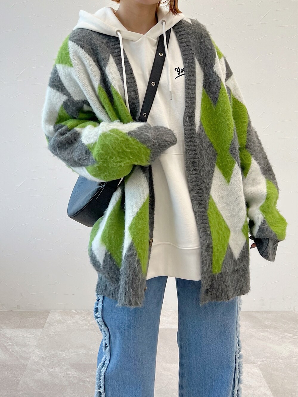 ブルー系のデニムパンツ、ブラック系のブーツ、グリーン系のカーディガン/ボレロを着用したレディースの冬コーディネートの5枚目の写真