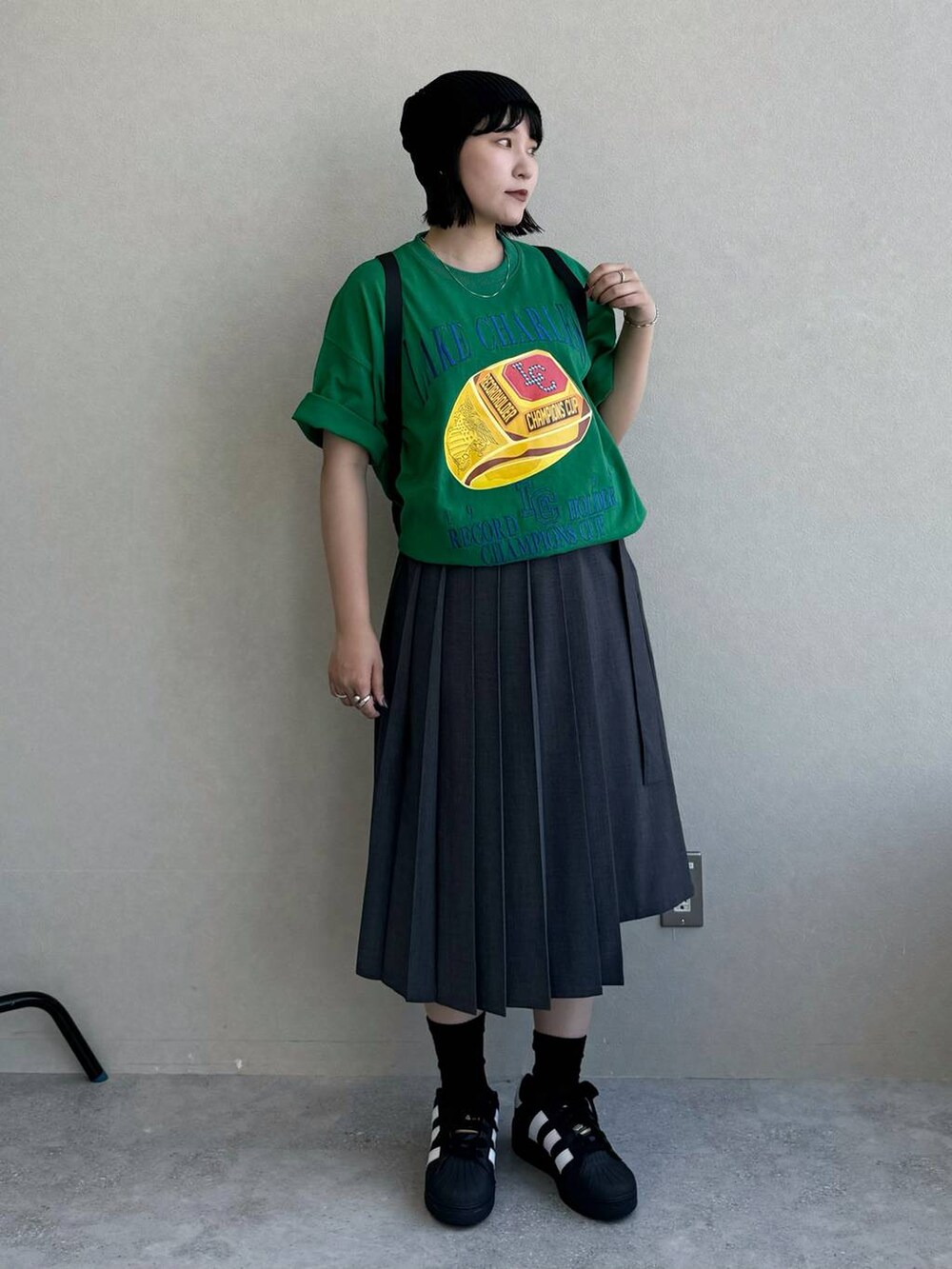 ブラック系のバックパック/リュック、グレー系のスカート、グリーン系のTシャツ/カットソーを着用したレディースの春コーディネートの2枚目の写真