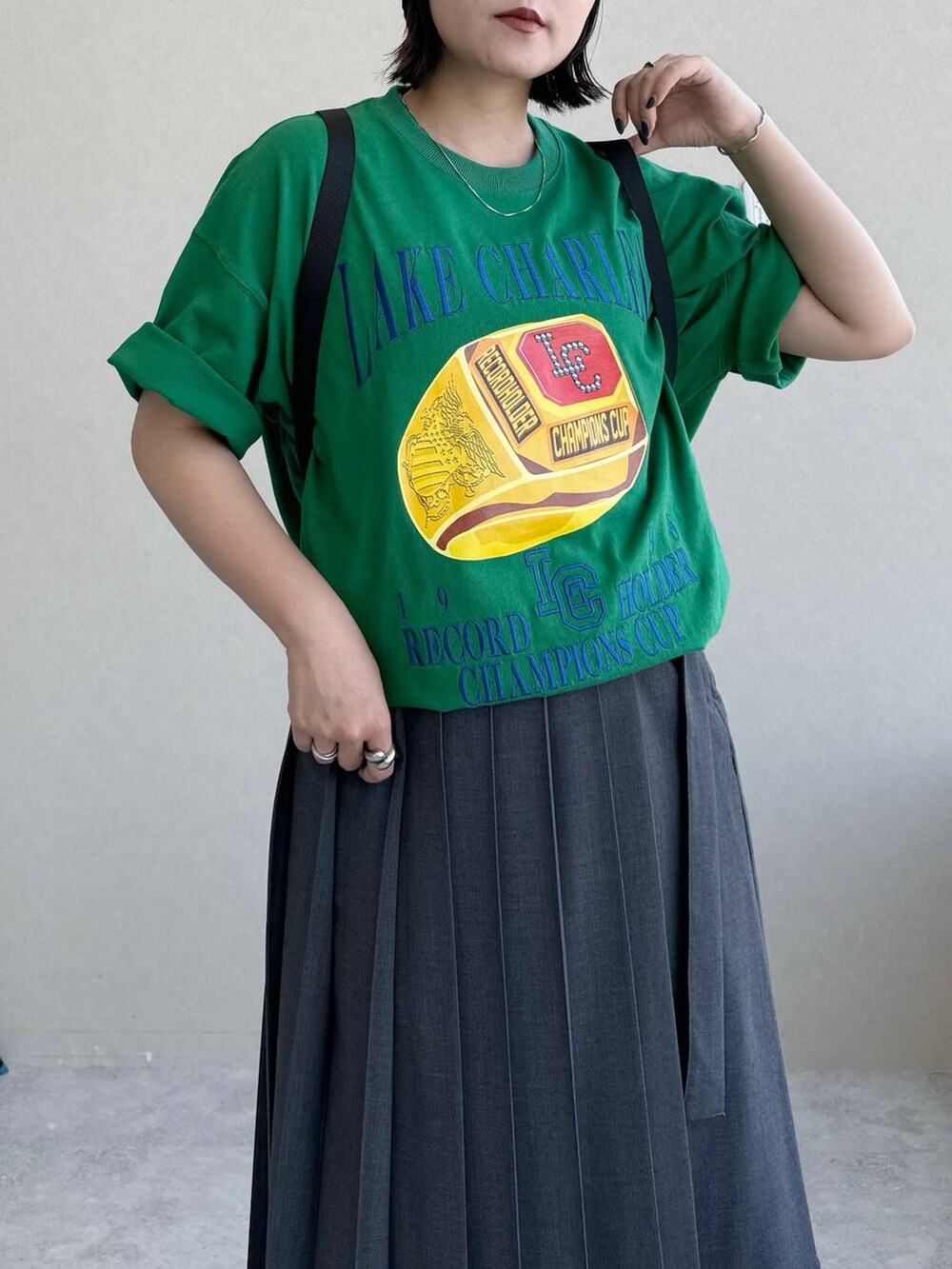 ブラック系のバックパック/リュック、グレー系のスカート、グリーン系のTシャツ/カットソーを着用したレディースの春コーディネートの4枚目の写真