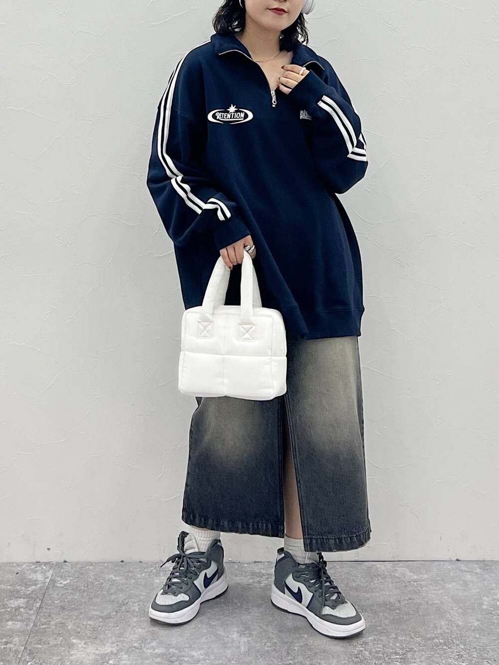 ホワイト系のハンドバッグ、ブラック系のスカート、ブルー系のスウェットを着用したレディースの秋コーディネートの2枚目の写真