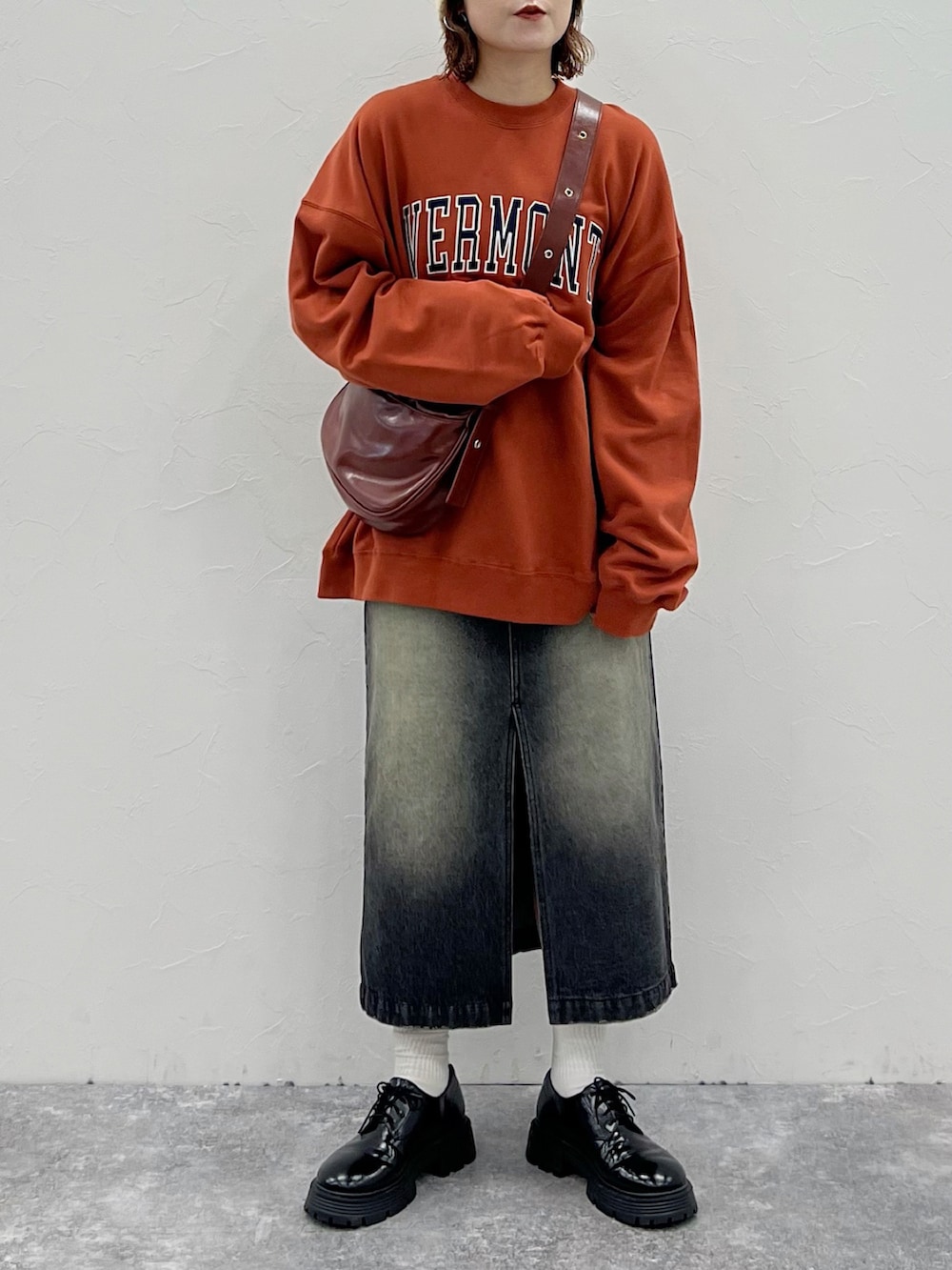 ブラック系のその他シューズ、ブラック系のスカート、オレンジ系のスウェットを着用したレディースの秋コーディネートの3枚目の写真