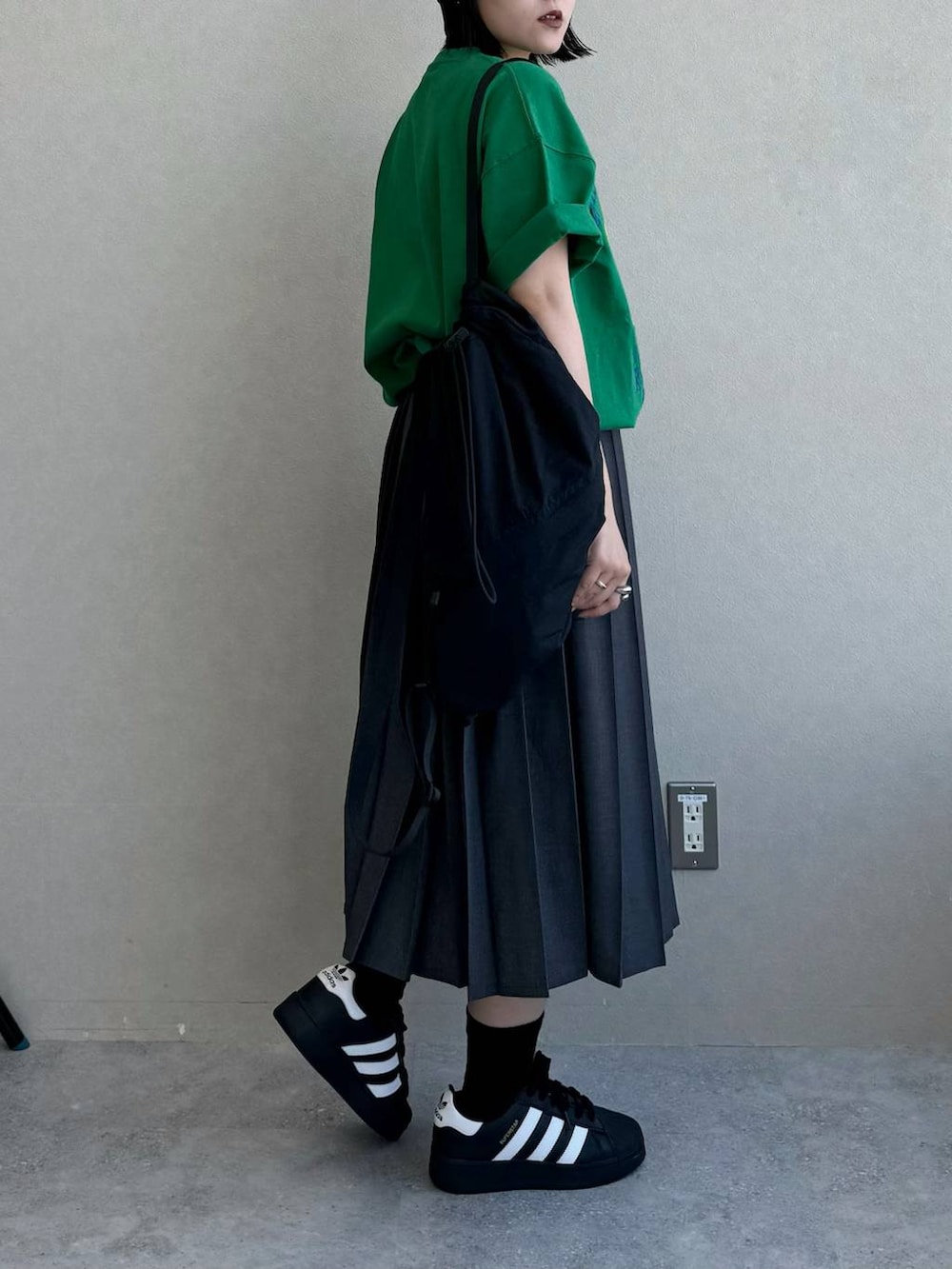 ブラック系のバックパック/リュック、グレー系のスカート、グリーン系のTシャツ/カットソーを着用したレディースの春コーディネートの3枚目の写真