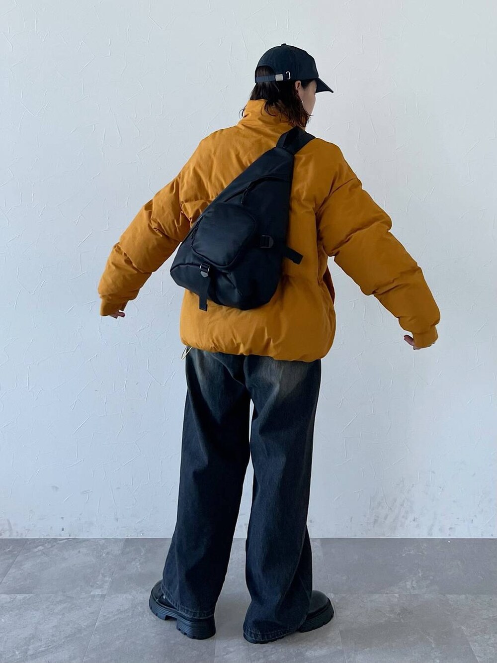 ブラック系のその他シューズ、ブラック系のデニムパンツ、イエロー系のダウンジャケット/コートを着用したレディースの秋コーディネートの2枚目の写真