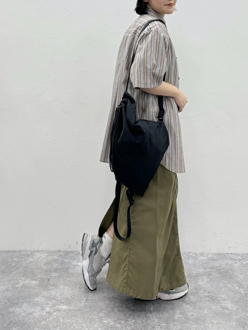 ブラック系のバックパック/リュック、グリーン系のスカート、ホワイト系のTシャツ/カットソーを着用したレディースの春コーディネートの3枚目の写真