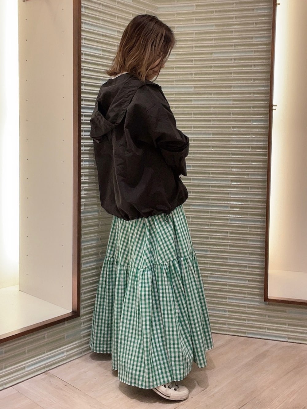 グリーン系のスカート、ブラック系のブルゾン、ホワイト系のTシャツ/カットソーを着用したレディースの春コーディネートの4枚目の写真