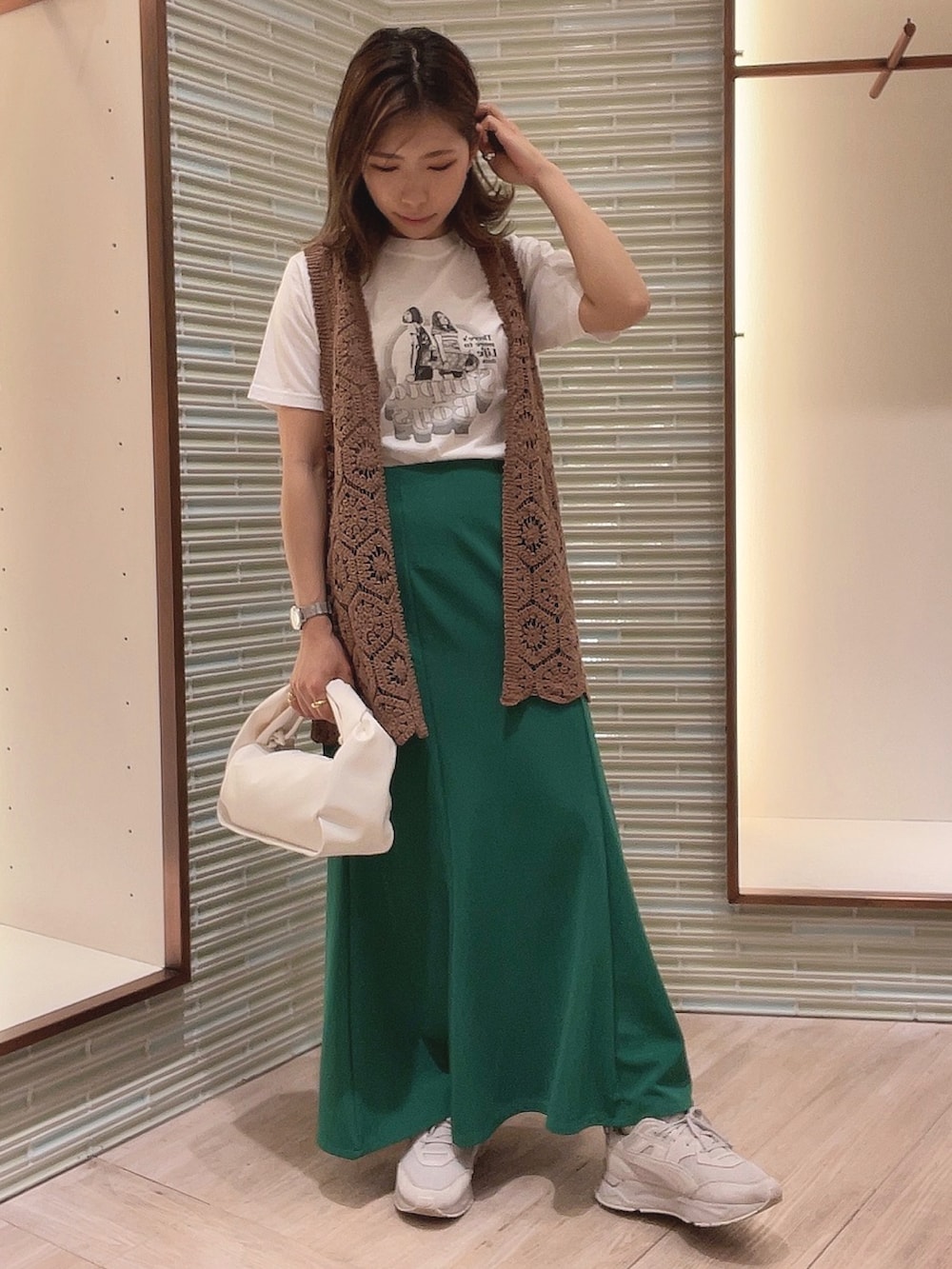 ホワイト系のTシャツ/カットソー、グリーン系のスカート、ブラウン系のベストを着用したレディースの春コーディネートの2枚目の写真