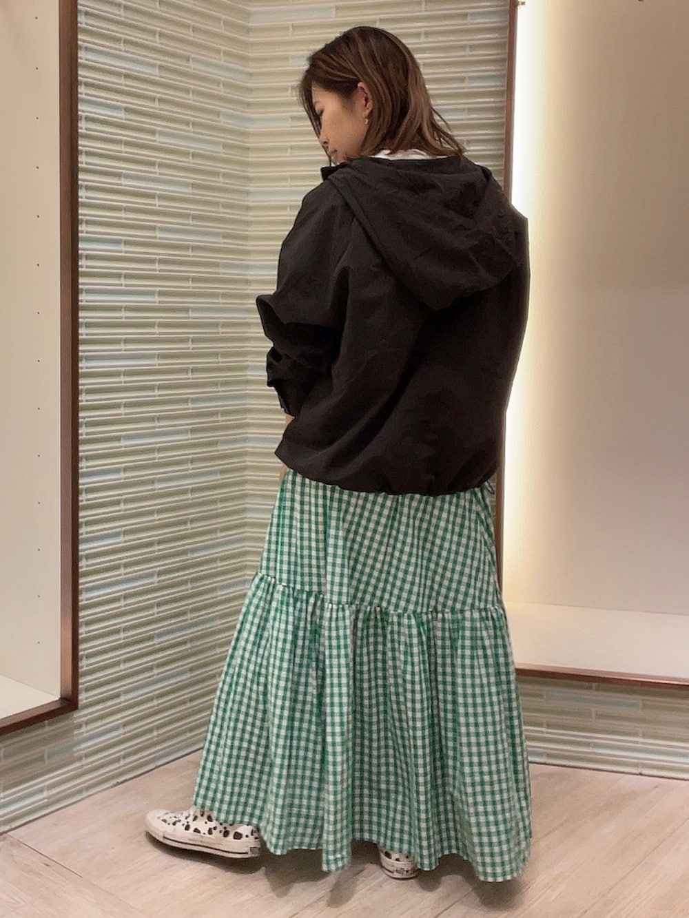 グリーン系のスカート、ブラック系のブルゾン、ホワイト系のTシャツ/カットソーを着用したレディースの春コーディネートの3枚目の写真