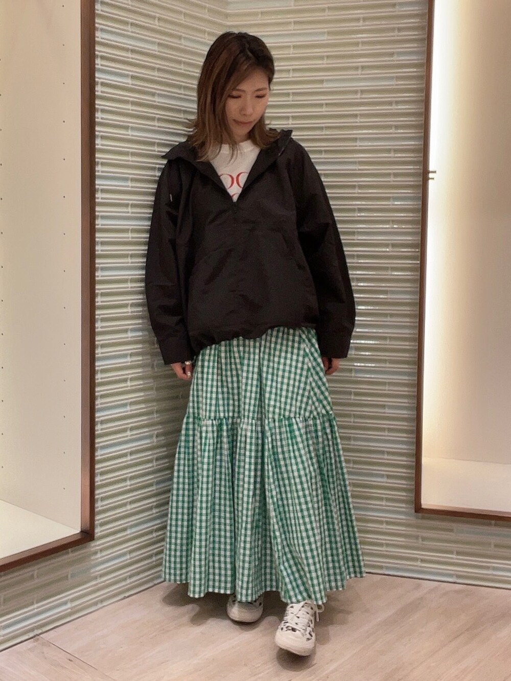 グリーン系のスカート、ブラック系のブルゾン、ホワイト系のTシャツ/カットソーを着用したレディースの春コーディネートの2枚目の写真