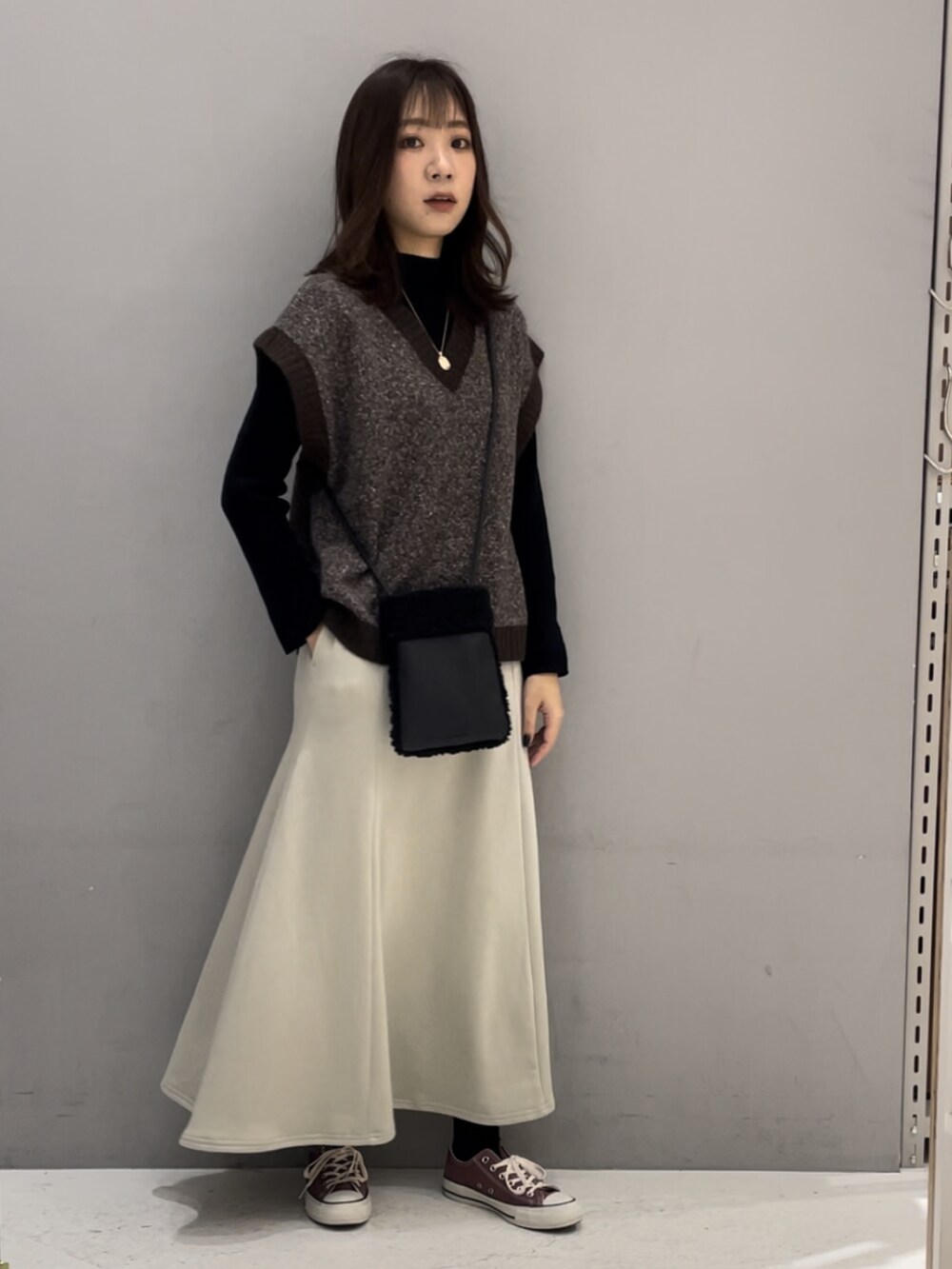 ブラウン系のベスト、ブラック系のニット/セーター、ベージュ系のスカートを着用したレディースの冬コーディネートの2枚目の写真