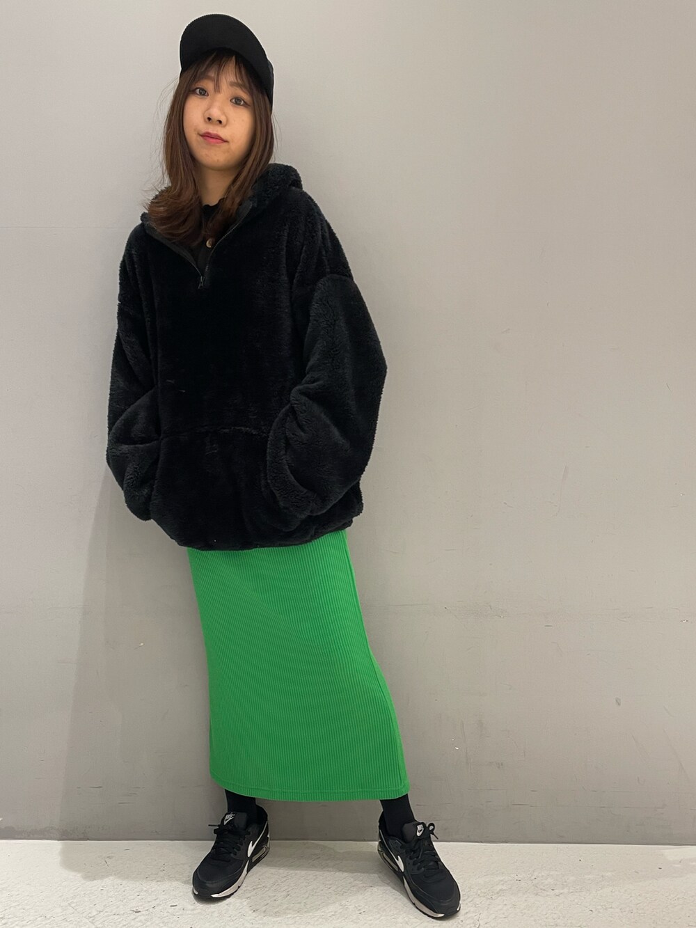 グリーン系のスカート、ブラック系のパーカーを着用したレディースの冬コーディネートの2枚目の写真