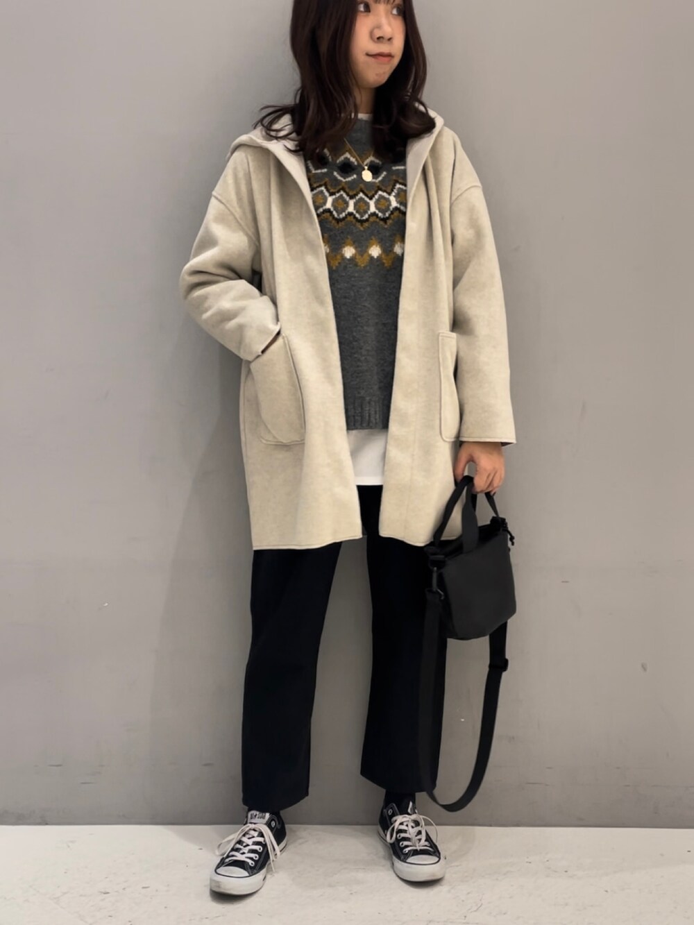 グレー系のニット/セーター、ブラック系のトートバッグ、ベージュ系のノーカラーコートを着用したレディースの冬コーディネートの2枚目の写真