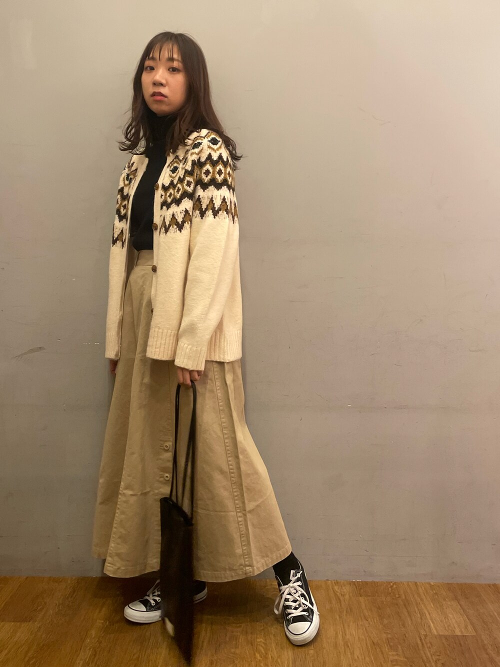 ホワイト系のカーディガン/ボレロ、ブラック系のニット/セーター、ベージュ系のスカートを着用したレディースの冬コーディネートの2枚目の写真