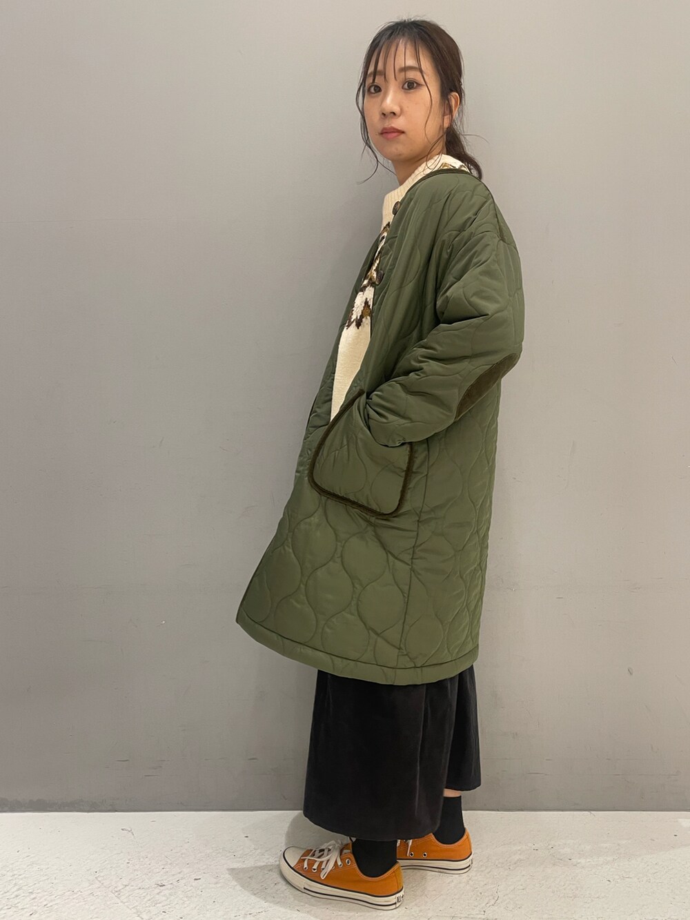 ホワイト系のニット/セーター、グリーン系のノーカラーコート、グレー系のスカートを着用したレディースの冬コーディネートの2枚目の写真