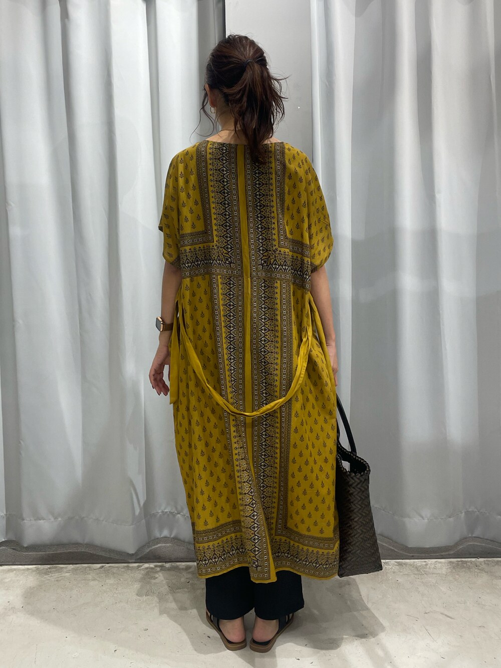 イエロー系のワンピース、ブラック系のその他パンツを着用したレディースの夏コーディネートの2枚目の写真