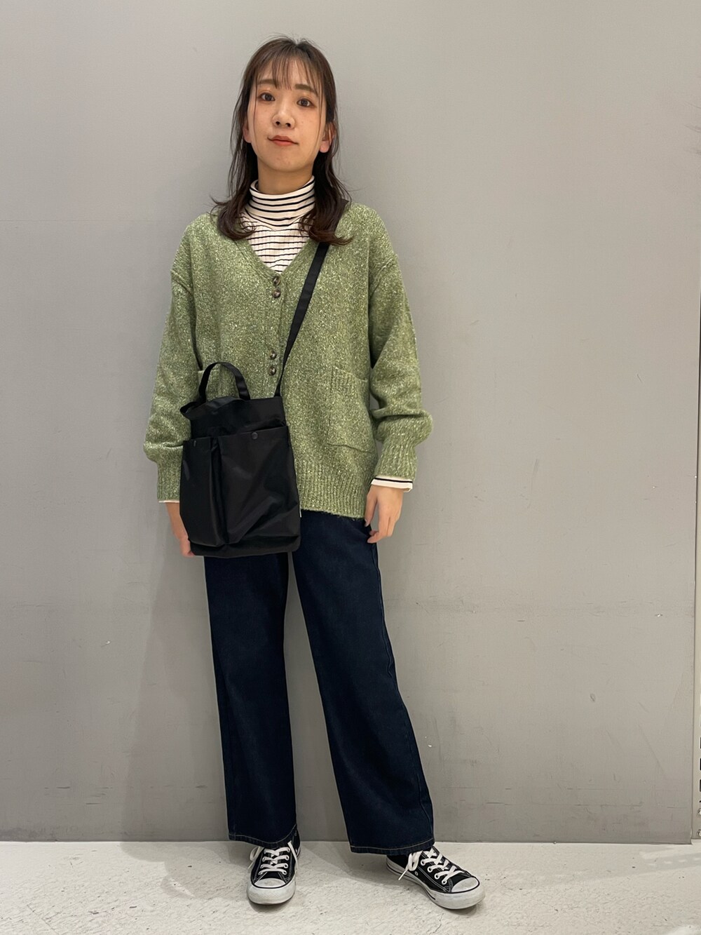 グリーン系のカーディガン/ボレロ、ブラック系のショルダーバッグ、ブルー系のデニムパンツを着用したレディースの冬コーディネートの2枚目の写真