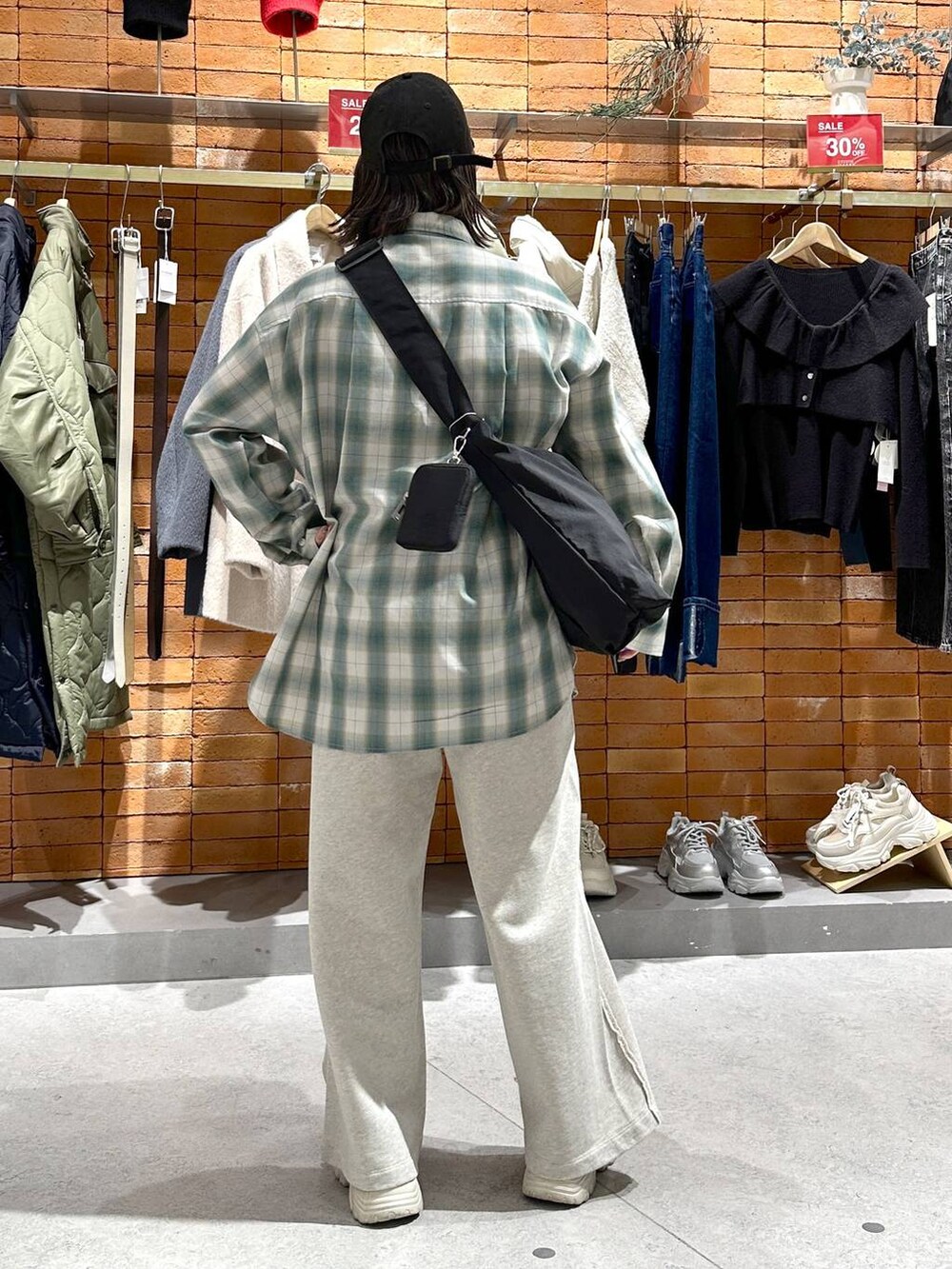 ブラック系のショルダーバッグ、ホワイト系のスニーカー、グリーン系のシャツ/ブラウスを着用したレディースの冬コーディネートの3枚目の写真