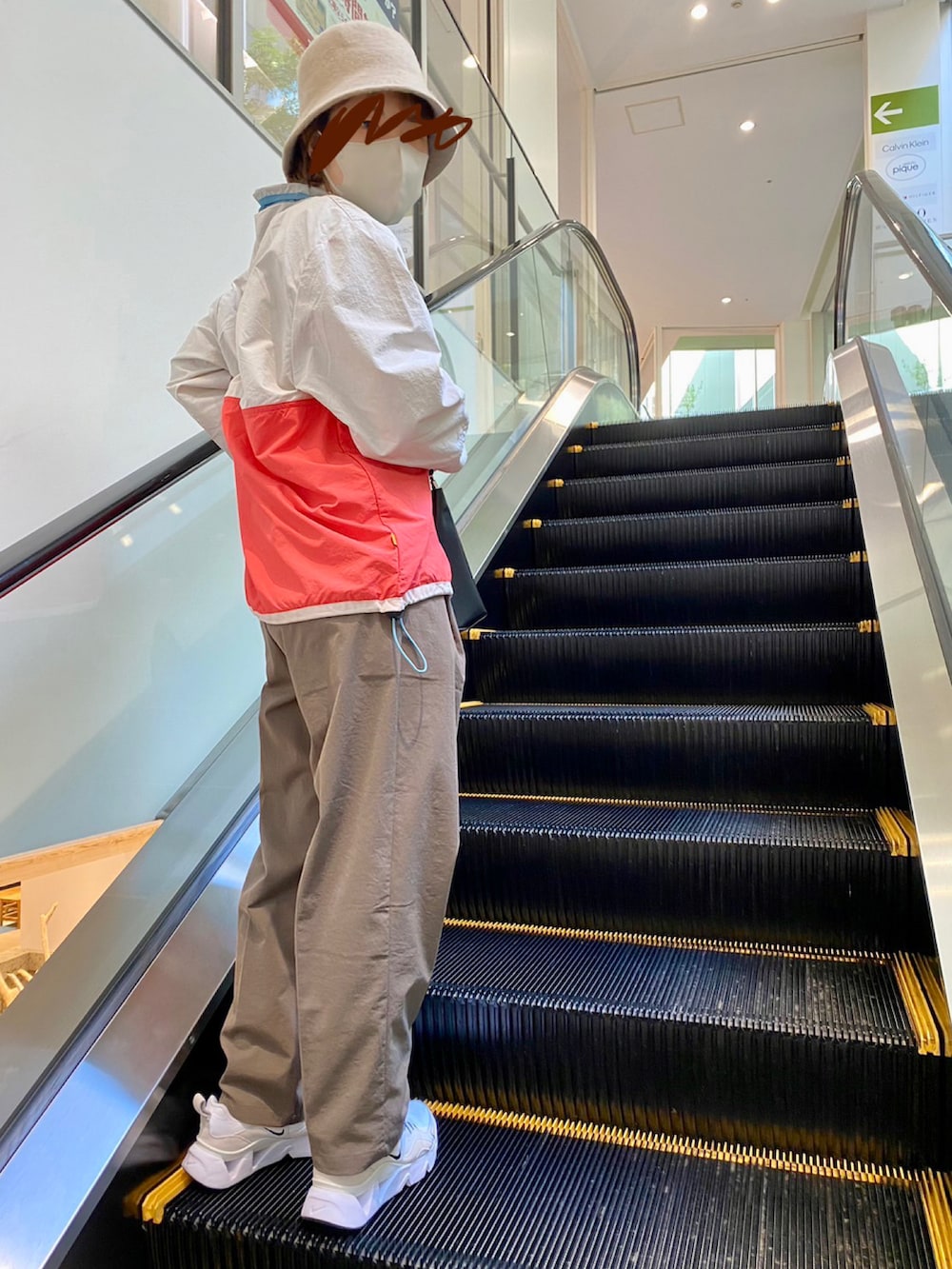 ブラウン系のスラックス、ホワイト系のナイロンジャケット、ブラック系のトートバッグを着用したレディースの冬コーディネートの2枚目の写真