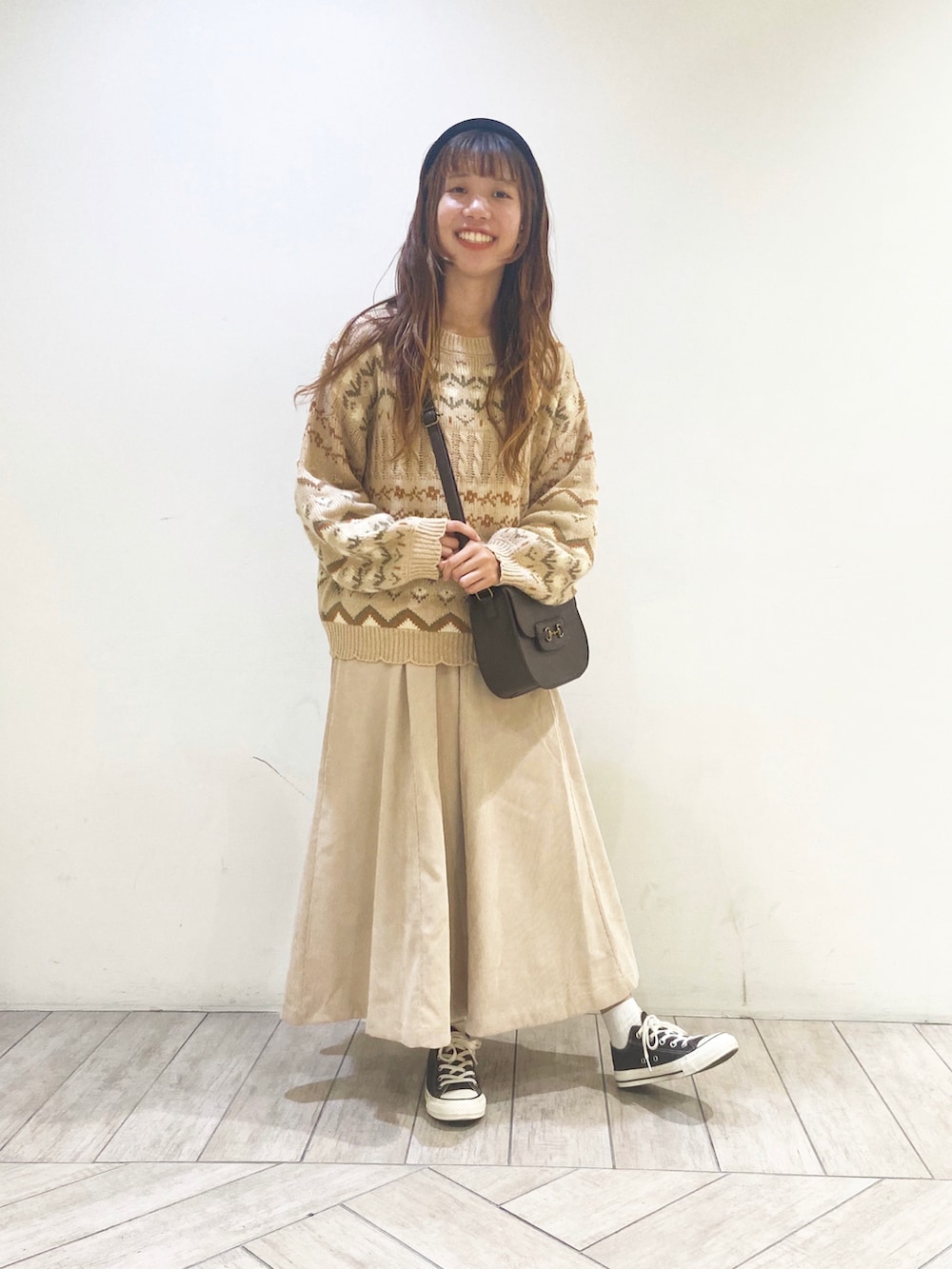 ベージュ系のニット/セーター、ブラウン系のショルダーバッグ、ベージュ系のスカートを着用したレディースの秋コーディネートの2枚目の写真