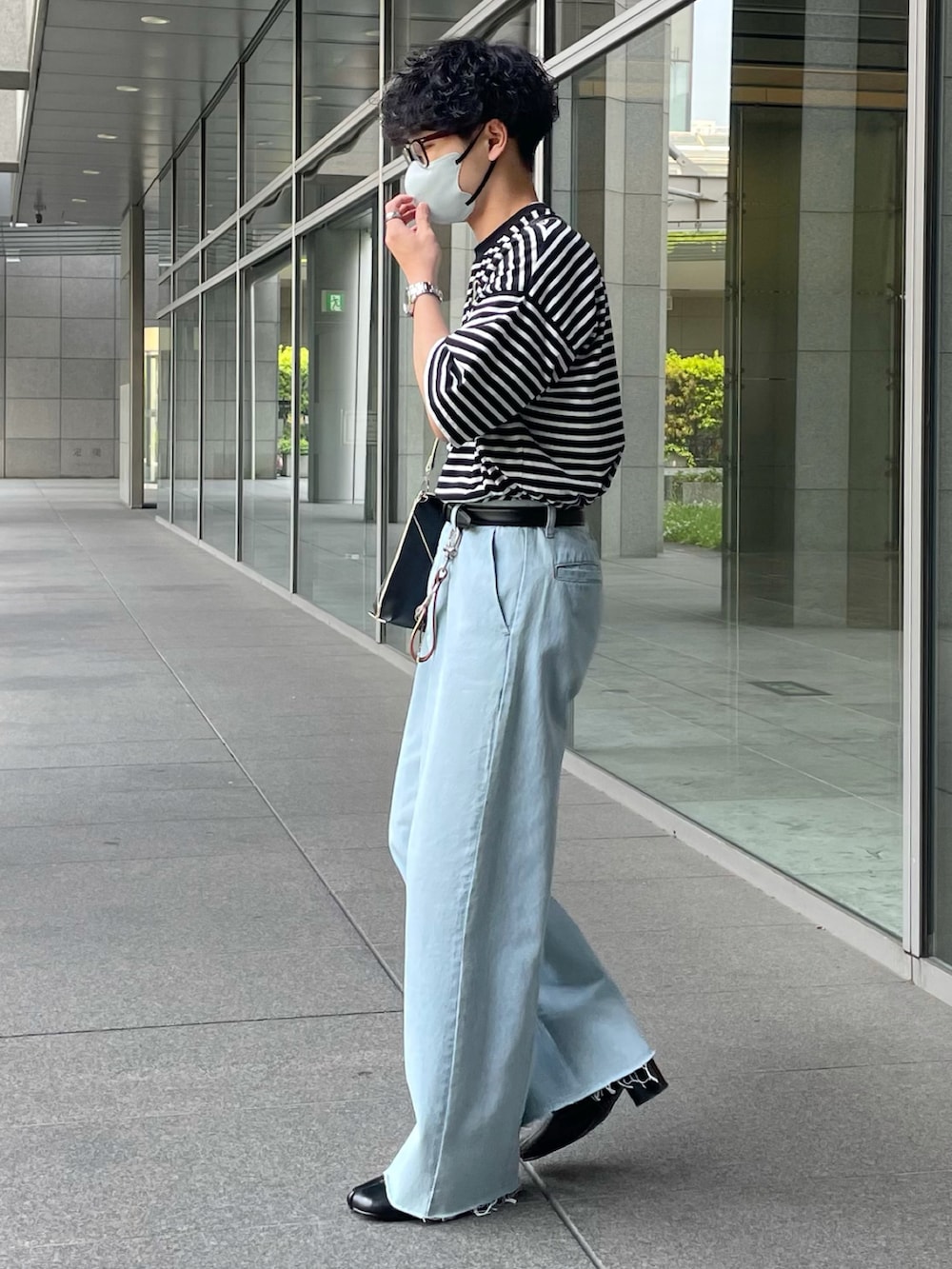 ブラック系のトップス、ブラック系のショルダーバッグ、ブルー系のデニムパンツを着用したメンズの春コーディネートの2枚目の写真