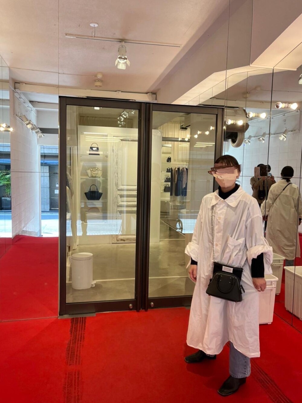 ブラック系のブーツ、ブルー系のデニムパンツ、ホワイト系のワンピースを着用したレディースの秋コーディネートの2枚目の写真