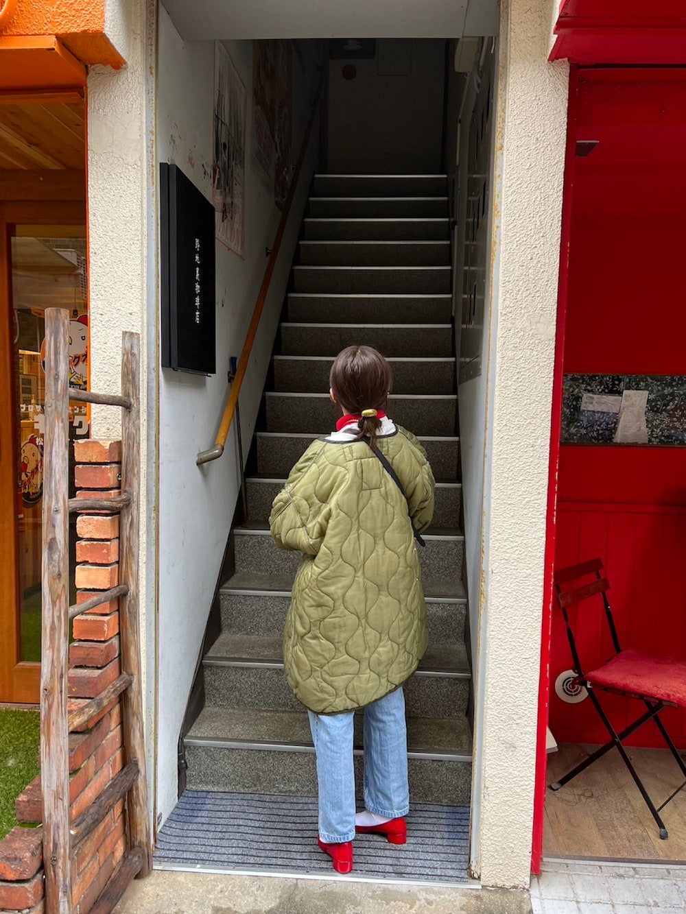 ブラック系のショルダーバッグ、ブルー系のデニムパンツ、レッド系のパンプスを着用したレディースの春コーディネートの2枚目の写真