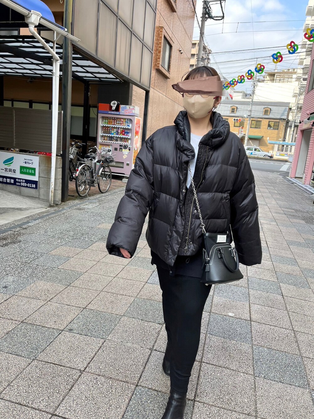 ブラック系のハンドバッグ、ブラック系のブーツ、ブラック系のダウンベストを着用したレディースの冬コーディネートの2枚目の写真