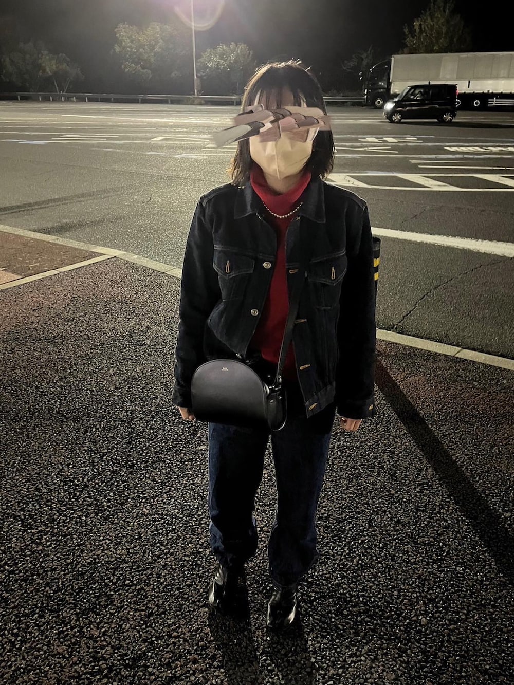 レッド系のニット/セーター、ブラック系のショルダーバッグ、ブルー系のデニムパンツを着用したレディースの冬コーディネートの2枚目の写真