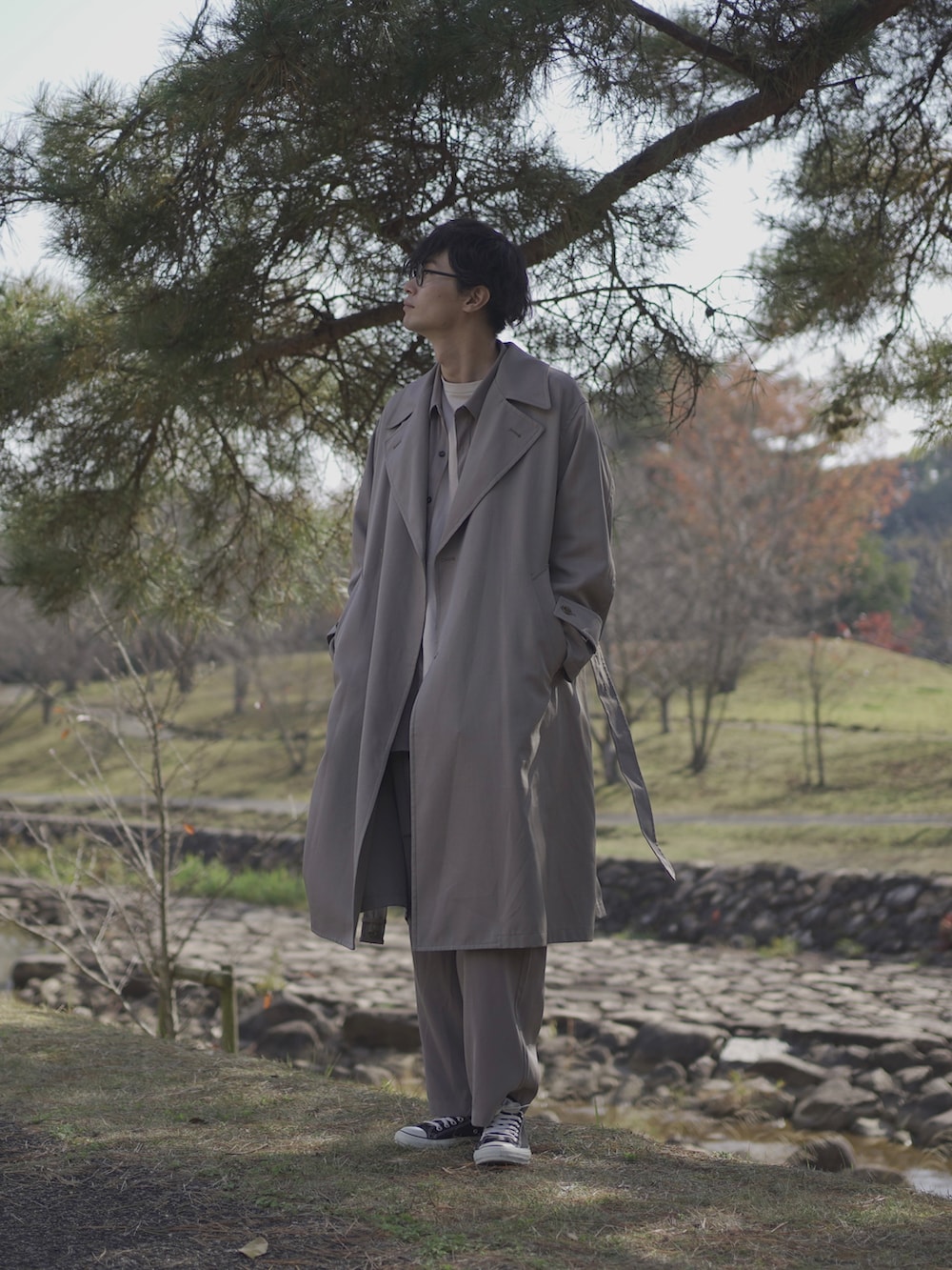 ベージュ系のトレンチコート、グレー系のシャツ/ブラウス、ベージュ系のTシャツ/カットソーを着用したメンズの冬コーディネートの3枚目の写真