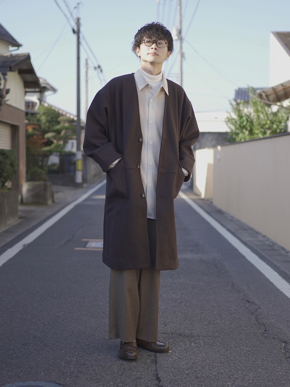 ブラウン系のノーカラーコート、ベージュ系のシャツ/ブラウス、ホワイト系のTシャツ/カットソーを着用したメンズの秋コーディネートの3枚目の写真