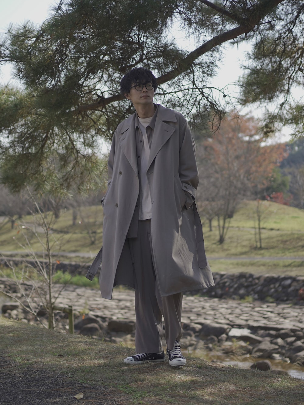 ベージュ系のトレンチコート、グレー系のシャツ/ブラウス、ベージュ系のTシャツ/カットソーを着用したメンズの冬コーディネートの2枚目の写真