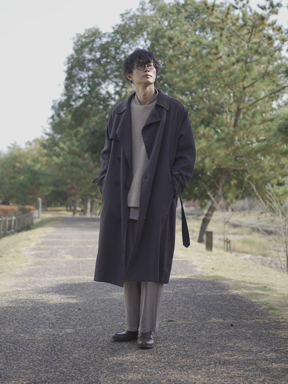 グレー系のトレンチコート、ベージュ系のニット/セーター、グレー系のシャツ/ブラウスを着用したメンズの冬コーディネートの4枚目の写真