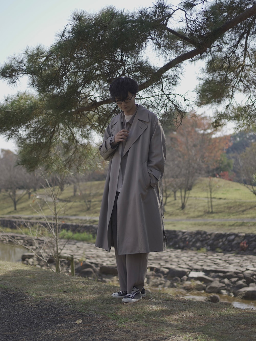 ベージュ系のトレンチコート、グレー系のシャツ/ブラウス、ベージュ系のTシャツ/カットソーを着用したメンズの冬コーディネートの4枚目の写真