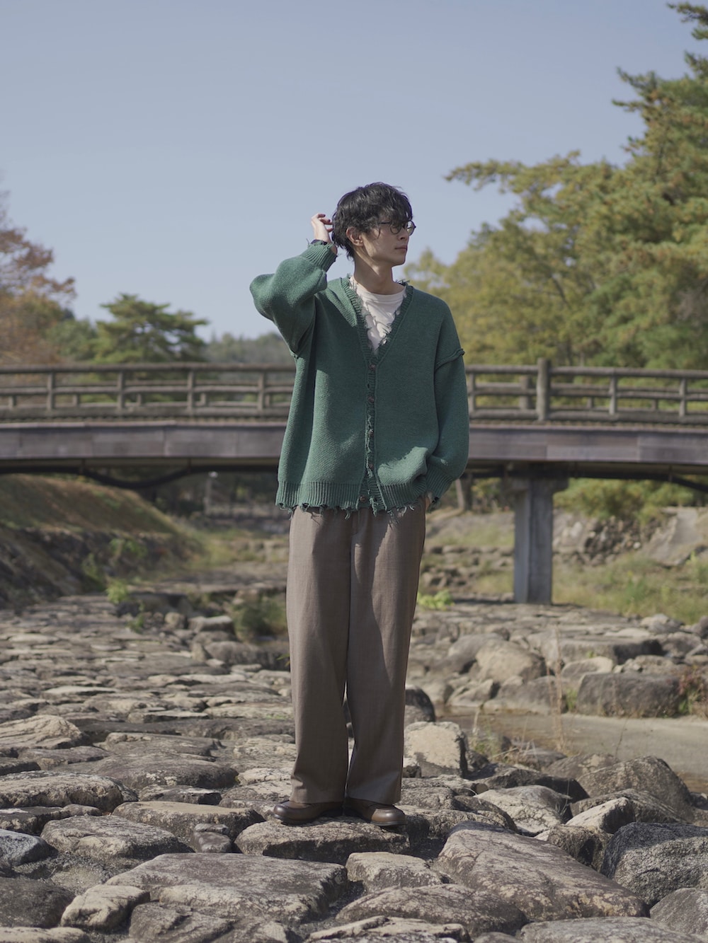 グリーン系のカーディガン/ボレロ、ベージュ系のTシャツ/カットソー、ブラウン系のスラックスを着用したメンズの秋コーディネートの3枚目の写真