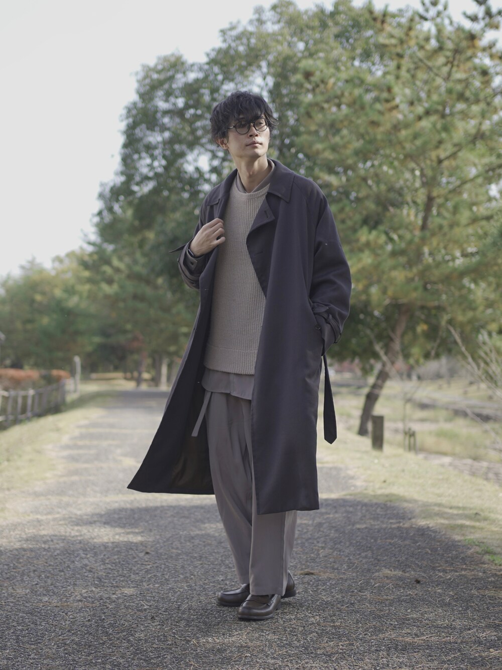 グレー系のトレンチコート、ベージュ系のニット/セーター、グレー系のシャツ/ブラウスを着用したメンズの冬コーディネートの2枚目の写真