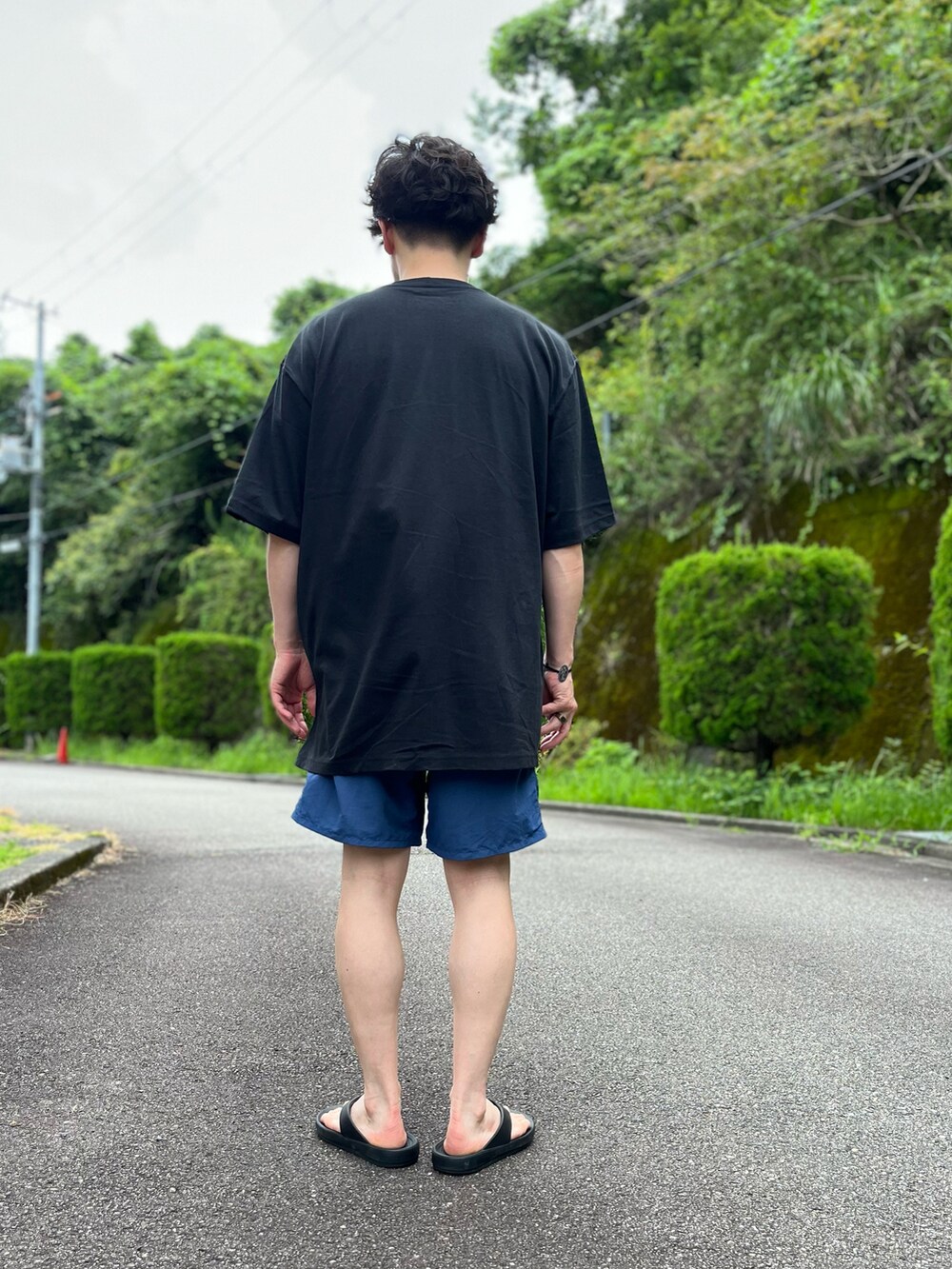 ブラック系のTシャツ/カットソー、ブルー系のパンツ、ブラック系のサンダルを着用したメンズの夏コーディネートの3枚目の写真