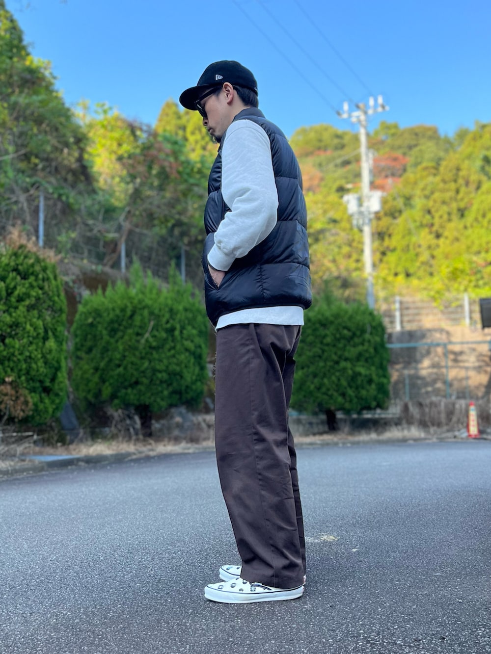 グレー系のスウェット、ブラック系のダウンベスト、ブラウン系のチノパンツを着用したメンズの秋コーディネートの4枚目の写真