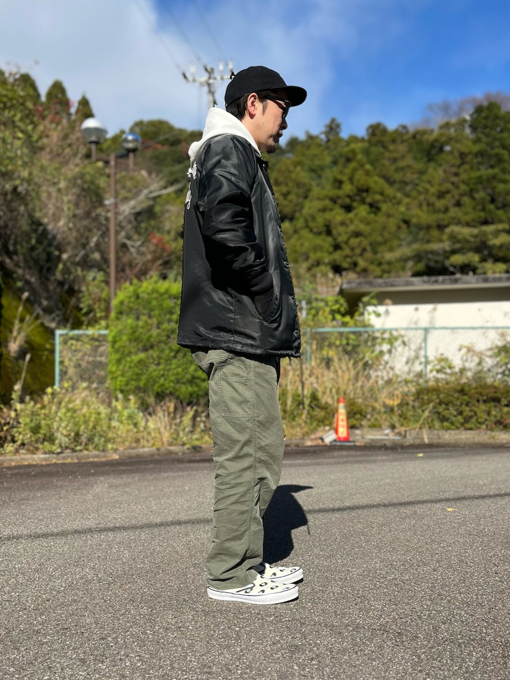 ホワイト系のパーカー、ブラック系のナイロンジャケット、グリーン系のパンツを着用したメンズの冬コーディネートの4枚目の写真