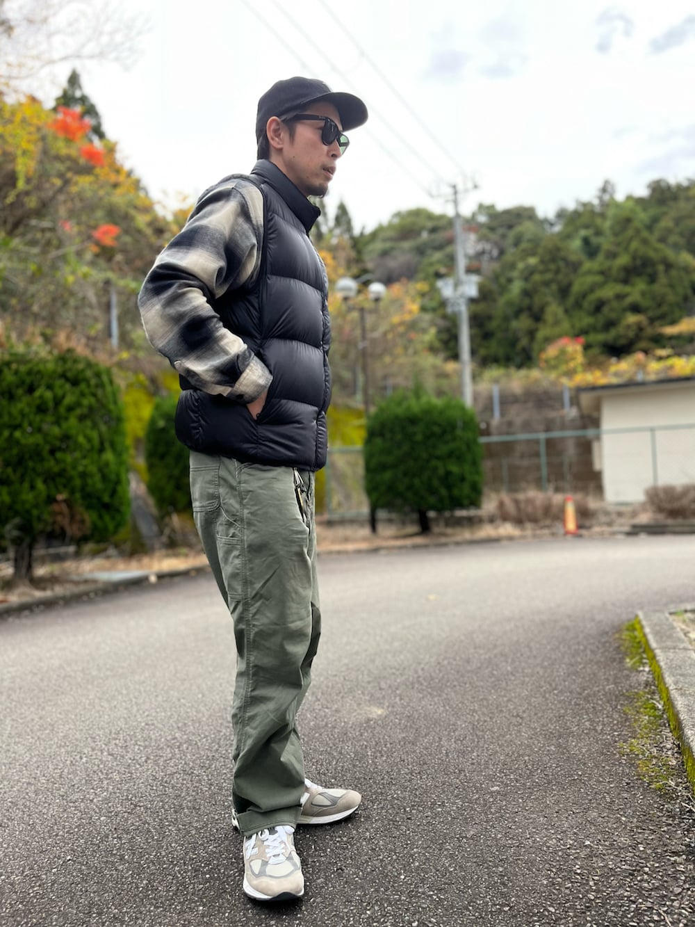 ブラック系のダウンベスト、ブラック系のトップス、グリーン系のパンツを着用したメンズの冬コーディネートの2枚目の写真
