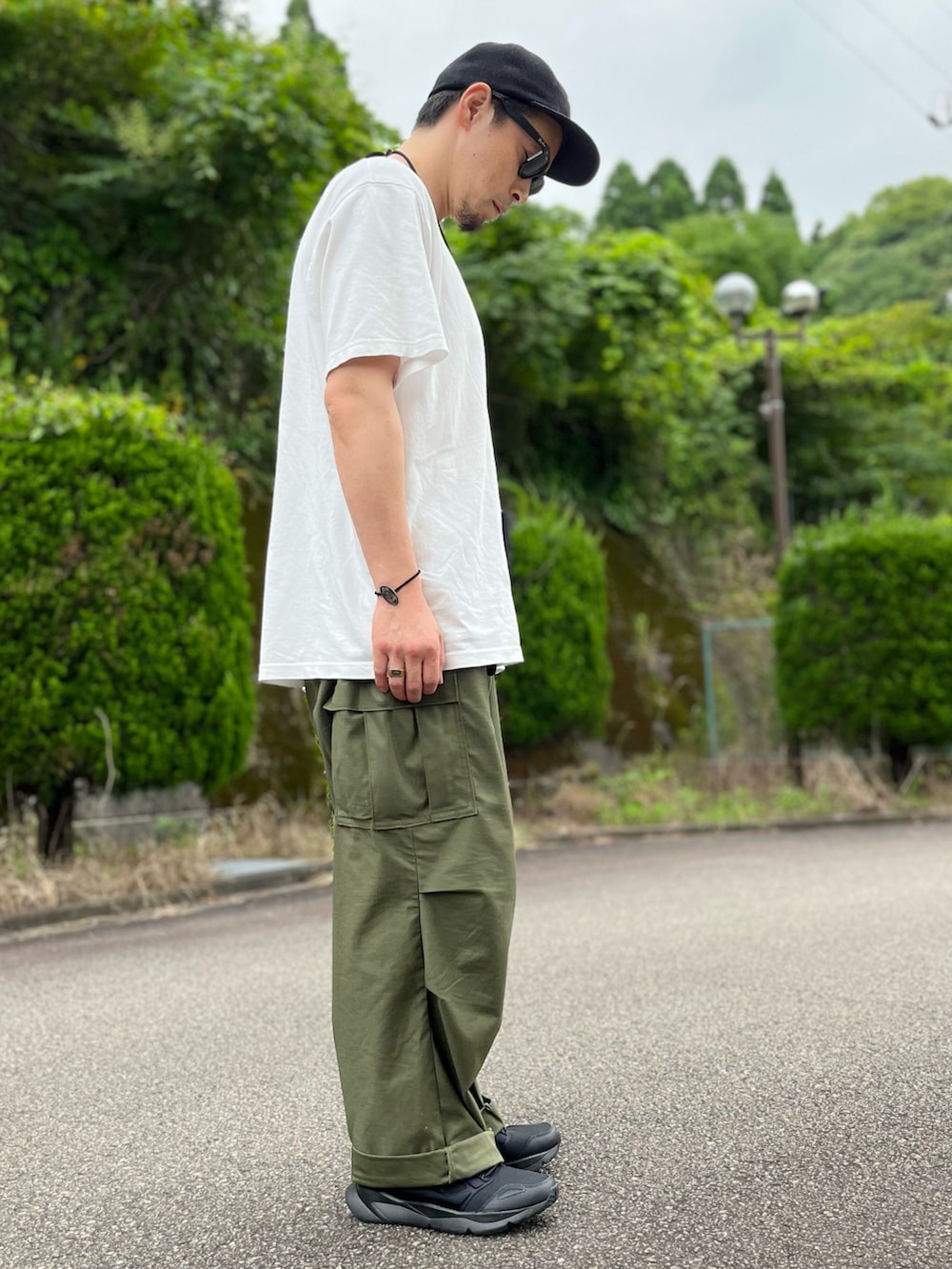 ホワイト系のTシャツ/カットソー、グリーン系のカーゴパンツ、ブラック系のスニーカーを着用したメンズの夏コーディネートの4枚目の写真