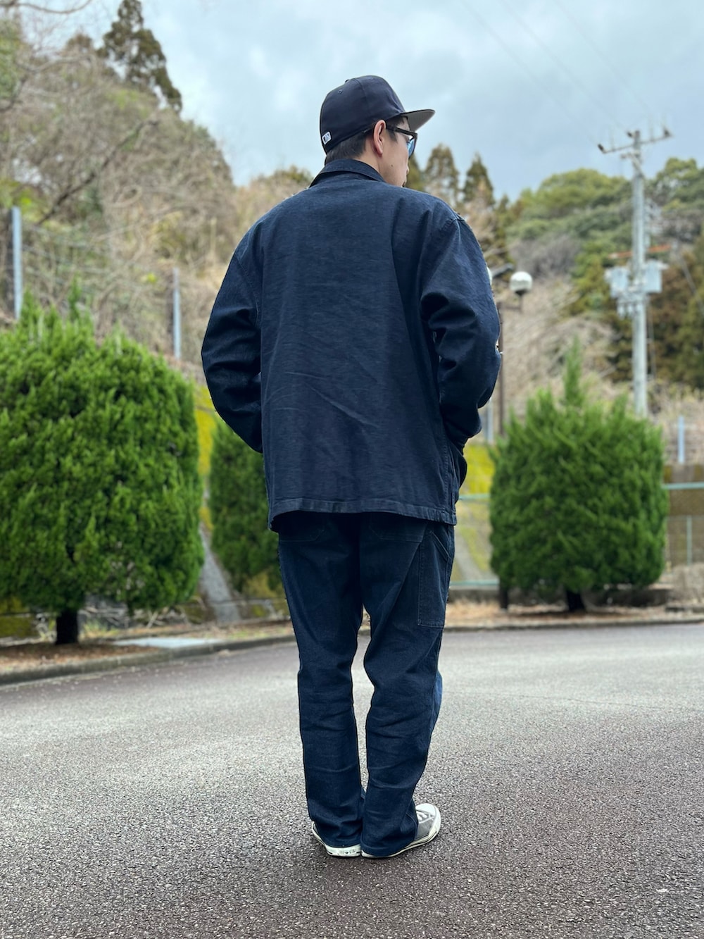 グレー系のスウェット、ブルー系のカバーオール、ブルー系のパンツを着用したメンズの春コーディネートの3枚目の写真